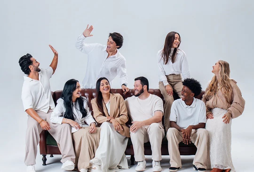 A equipe da Reino sentada no chão do estúdio, de branco e creme