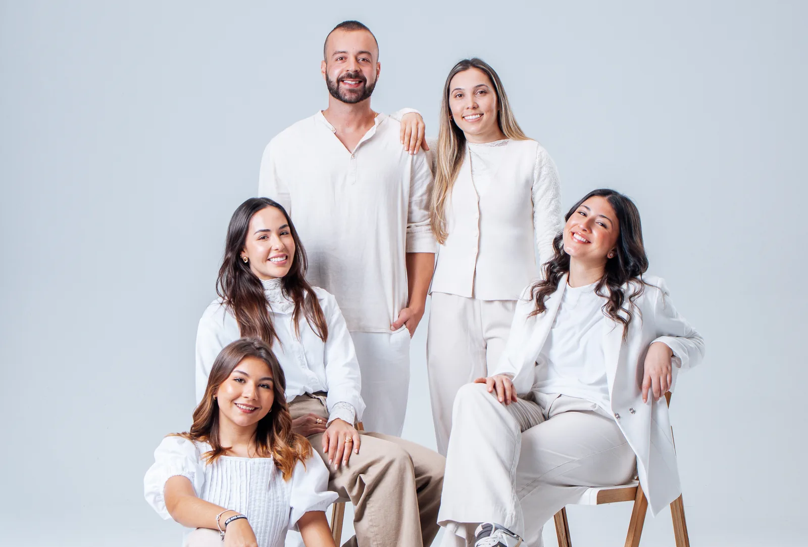 Cinco pessoas da Reino em volta de uma cadeira, de branco, no estúdio