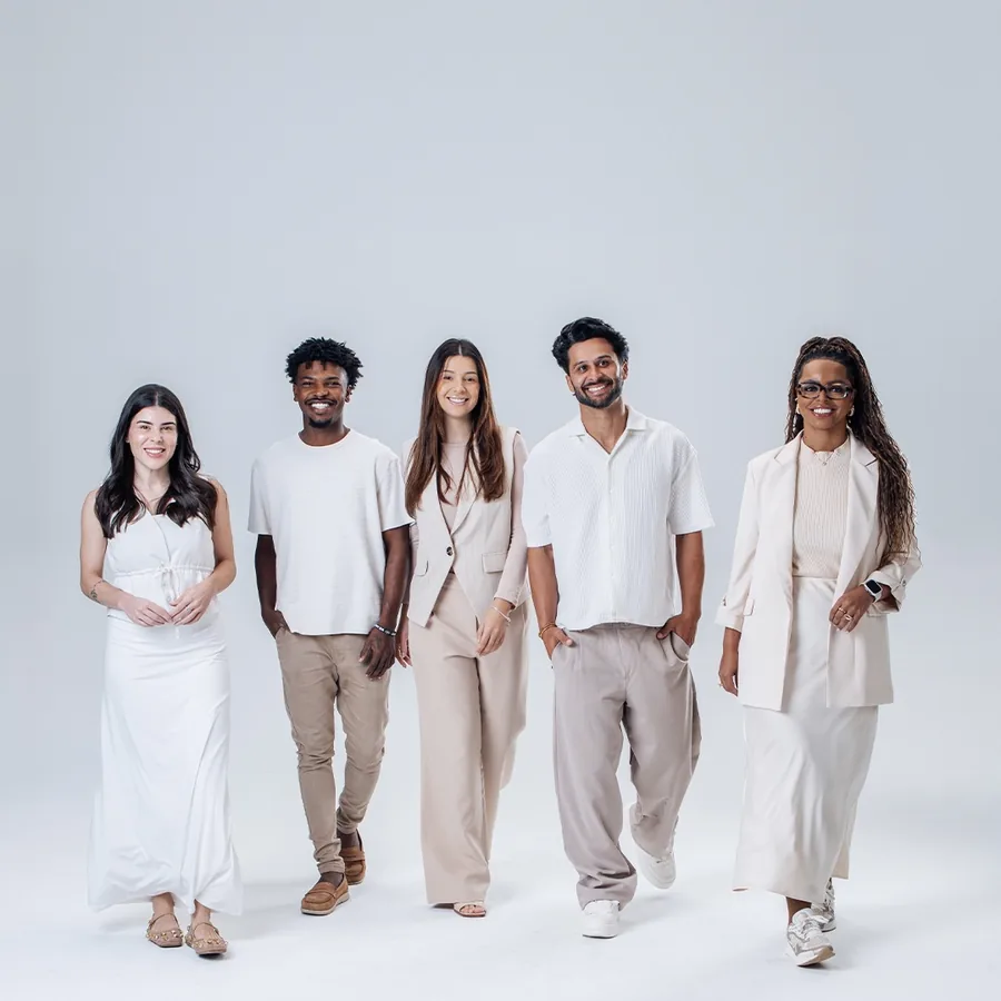 Cinco jovens em pé, de branco e creme, no estúdio