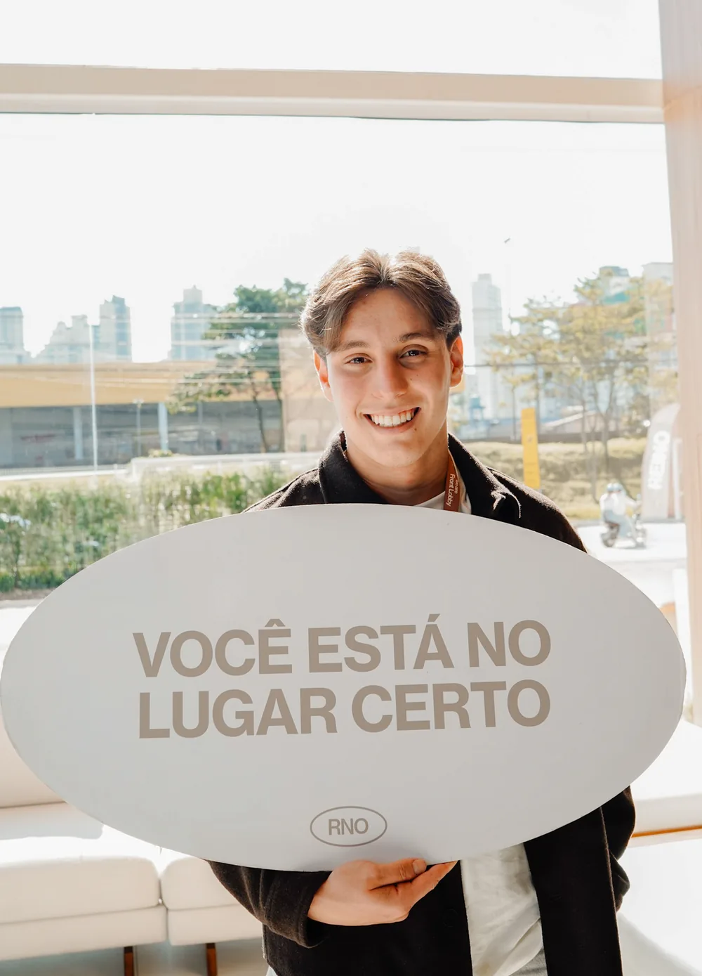 Menino sorri segurando a placa 'Você está no lugar certo'
